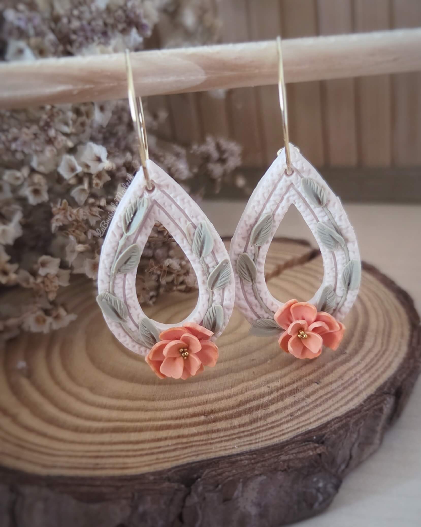 Detalle de flores naranjas modeladas a mano en pendientes Caléndula