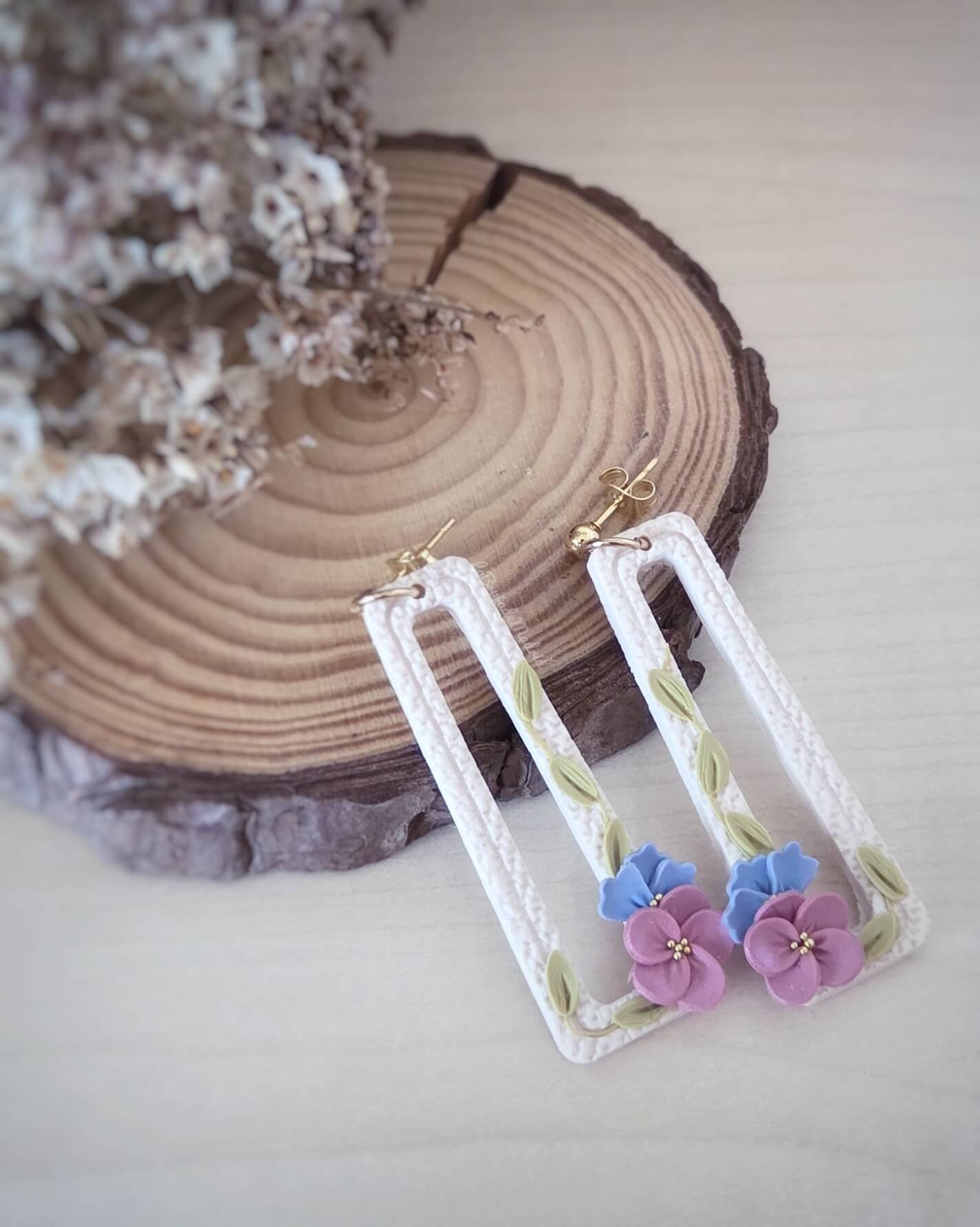 Pendientes Pensamientos hechos a mano con flores malva y azul sobre base texturizada blanca