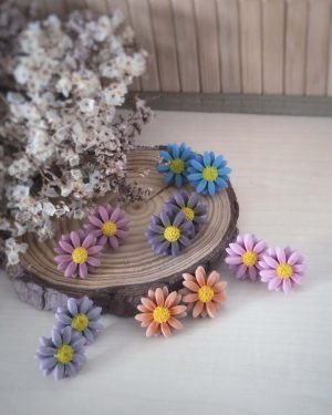 Colección de pendientes margarita en arcilla polimérica disponibles en seis colores: azul, morado, lila, rosa oscuro, rosa claro y naranja.