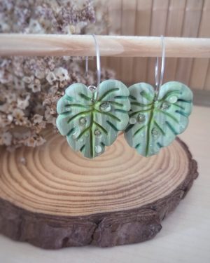 Pendientes artesanales de hoja Monstera en arcilla polimérica con tonos verdes, nervaduras pintadas a mano y gotas de rocío realizadas con resina.