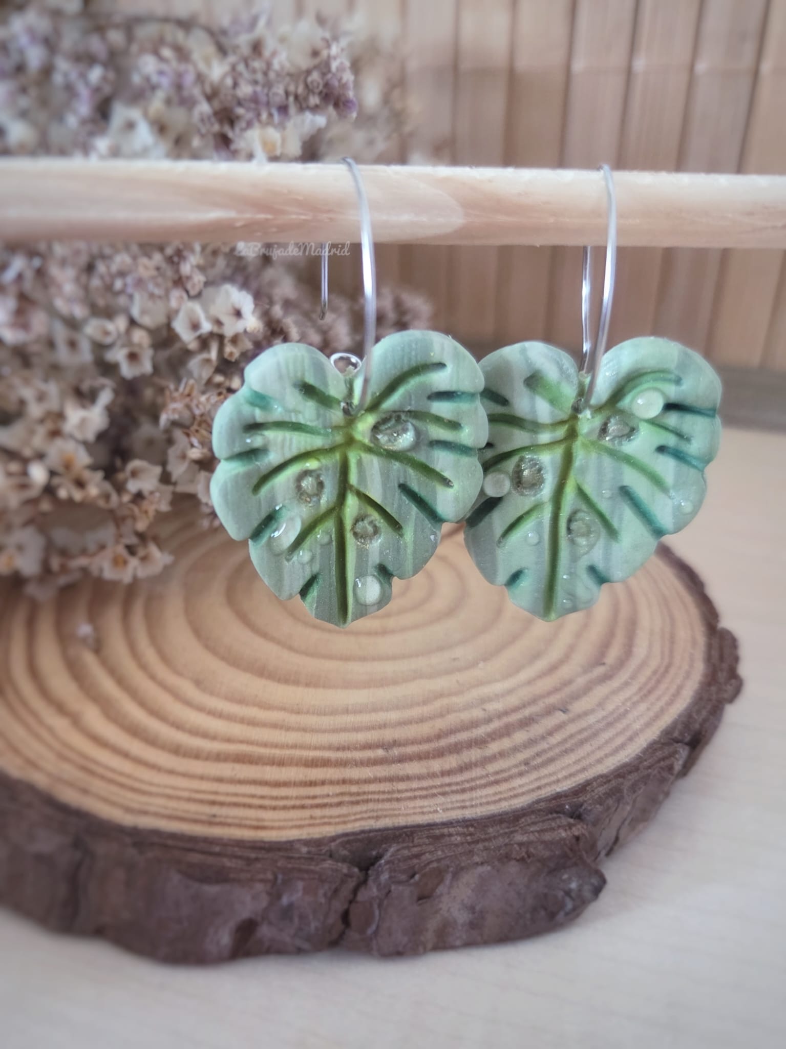 Pendientes artesanales de hoja Monstera en arcilla polimérica con tonos verdes, nervaduras pintadas a mano y gotas de rocío realizadas con resina.