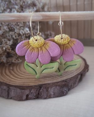 Pendientes artesanales de flor de equinácea en arcilla polimérica con pétalos rosas, centro amarillo y hojas verdes. Hechos a mano con arcilla polimerica y aros de acero inoxidable para orejitas sensibles.